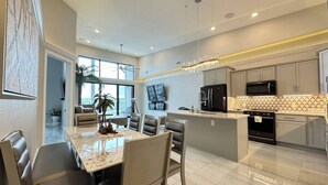 A modern kitchen with a central island, a dining area with a marble table, and a view of the outdoors. - Topsider Penthouse 511 with Resort Pools (Osage Beach)