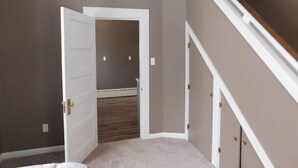 Ein Schlafzimmer mit einem großen Bett, einer Tür zu einem Flur und einer Treppe.