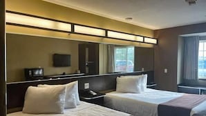 A hotel room with two beds, a large mirror, a flat-screen TV, and a window with curtains. - Motel 6 Breaux Bridge, La (Breaux Bridge)