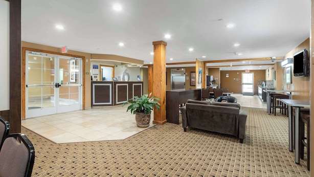 A spacious lobby with a reception desk, seating area, and a large potted plant. - Motel 6 Breaux Bridge, La (Breaux Bridge)
