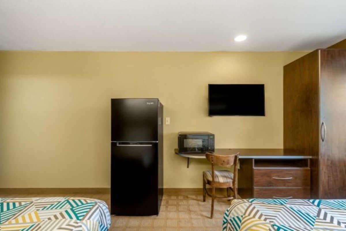 A hotel room with a bed, a refrigerator, a television, and a desk.
