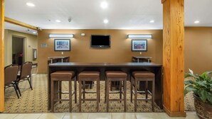 A conference room with a long table, four bar stools, a television, and framed pictures on the wall. - Studio 6 Suites - Breaux Bridge, La (Breaux Bridge)