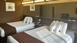 A hotel room with two beds, a nightstand, and a large mirror. - Studio 6 Suites - Breaux Bridge, La (Breaux Bridge)