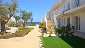 Un hotel moderno con scala centrale, area salotto esterna e vista sul mare.