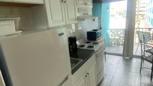 Cozinha com armários brancos, fogão, micro-ondas e cafeteira.