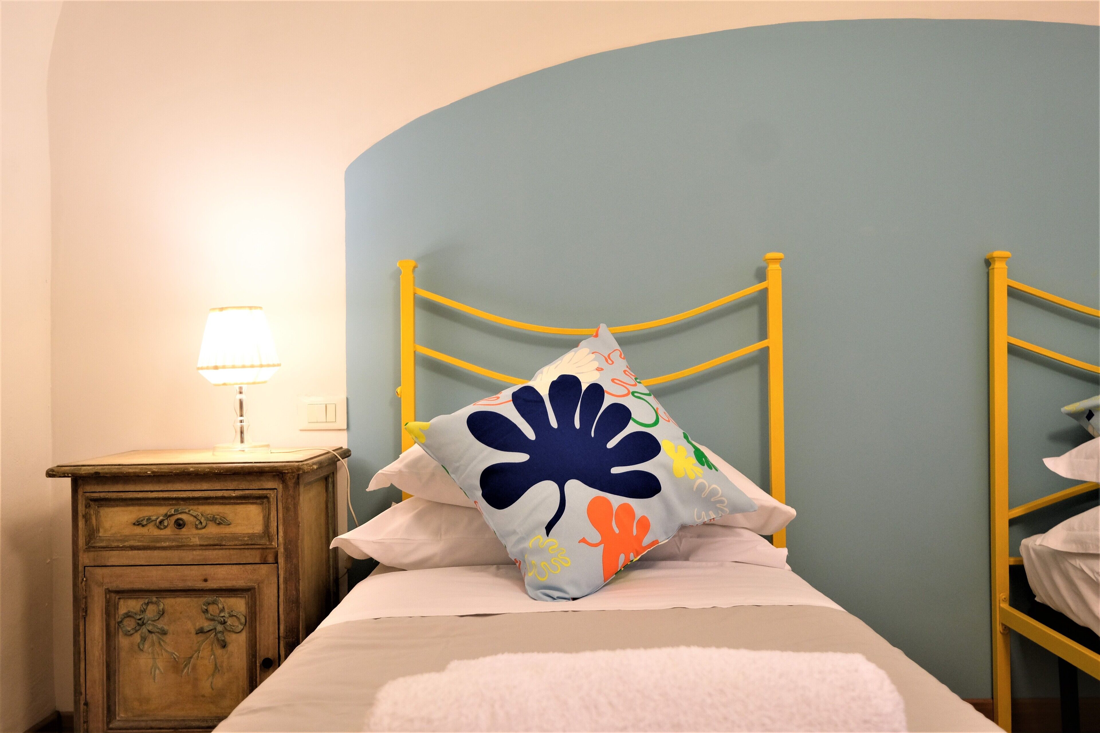 A bedroom with a bed, a nightstand, and a lamp.