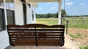 A porch with a wooden bench, a ceiling fan, and a view of a field. - The Red Gate - Branson & Eureka!
 (Green Forest)