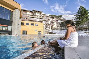 A swimming pool area with a view of a multi-story building in the background. - Belambra Club Les 2 Alpes Les Crêtes (Les Deux Alpes)