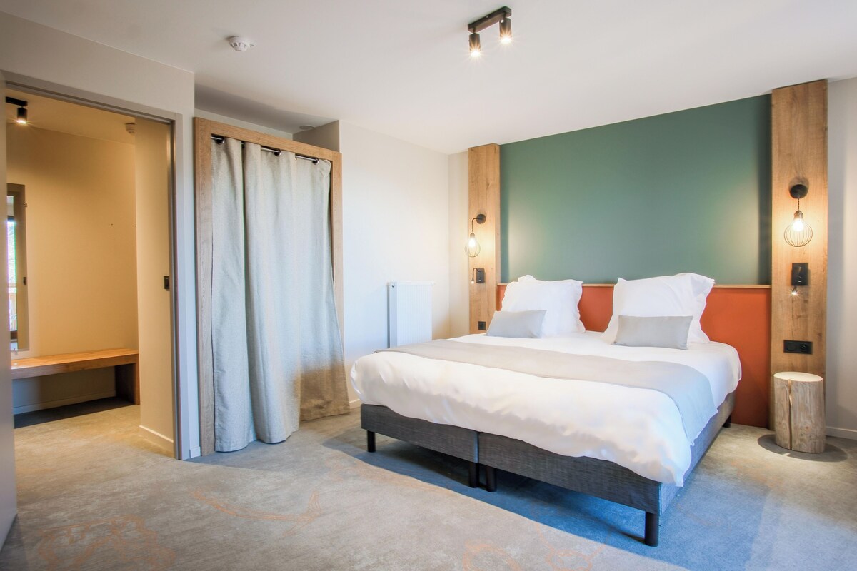 A modern bedroom with a large bed, a wooden headboard, and a view of the outdoors.