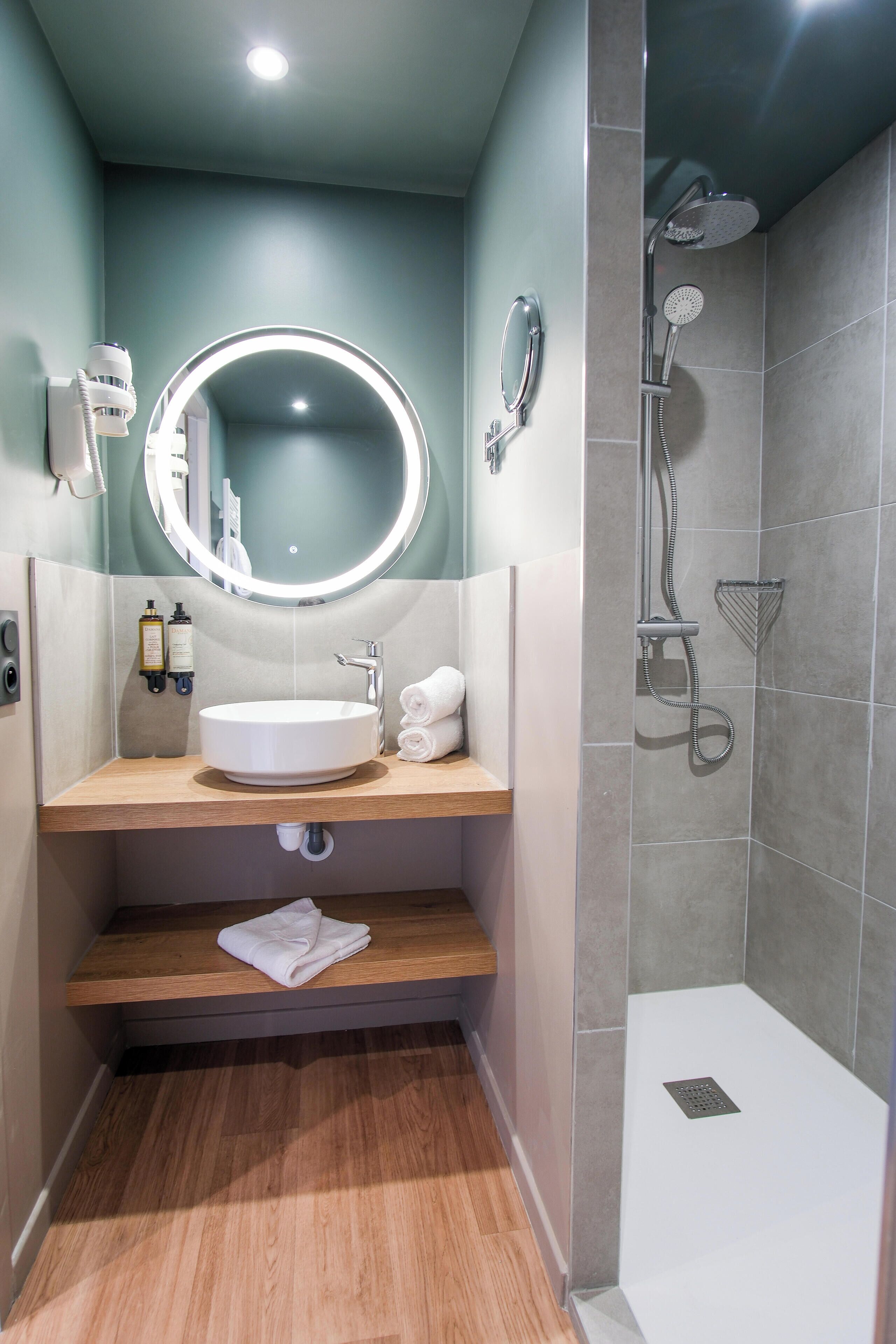 A modern bathroom with a round mirror, sink, and shower.