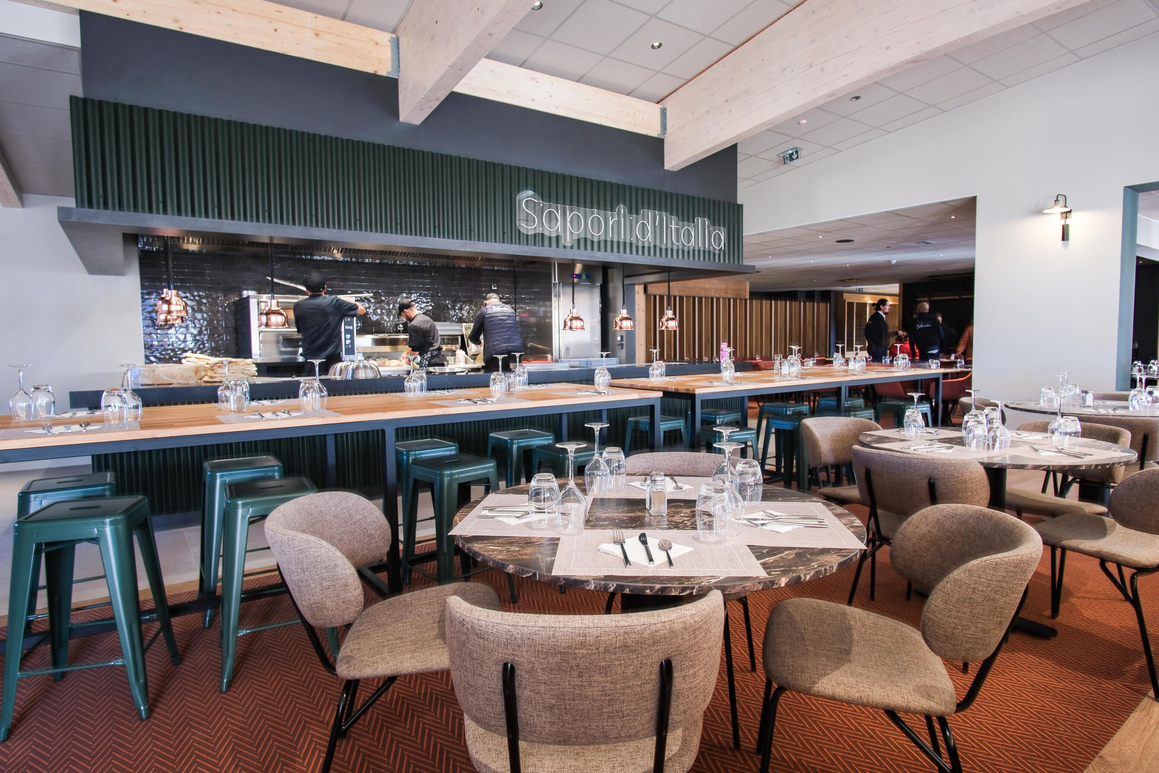 Un restaurant doté d’un bar, de plusieurs tables et de tabourets de bar.