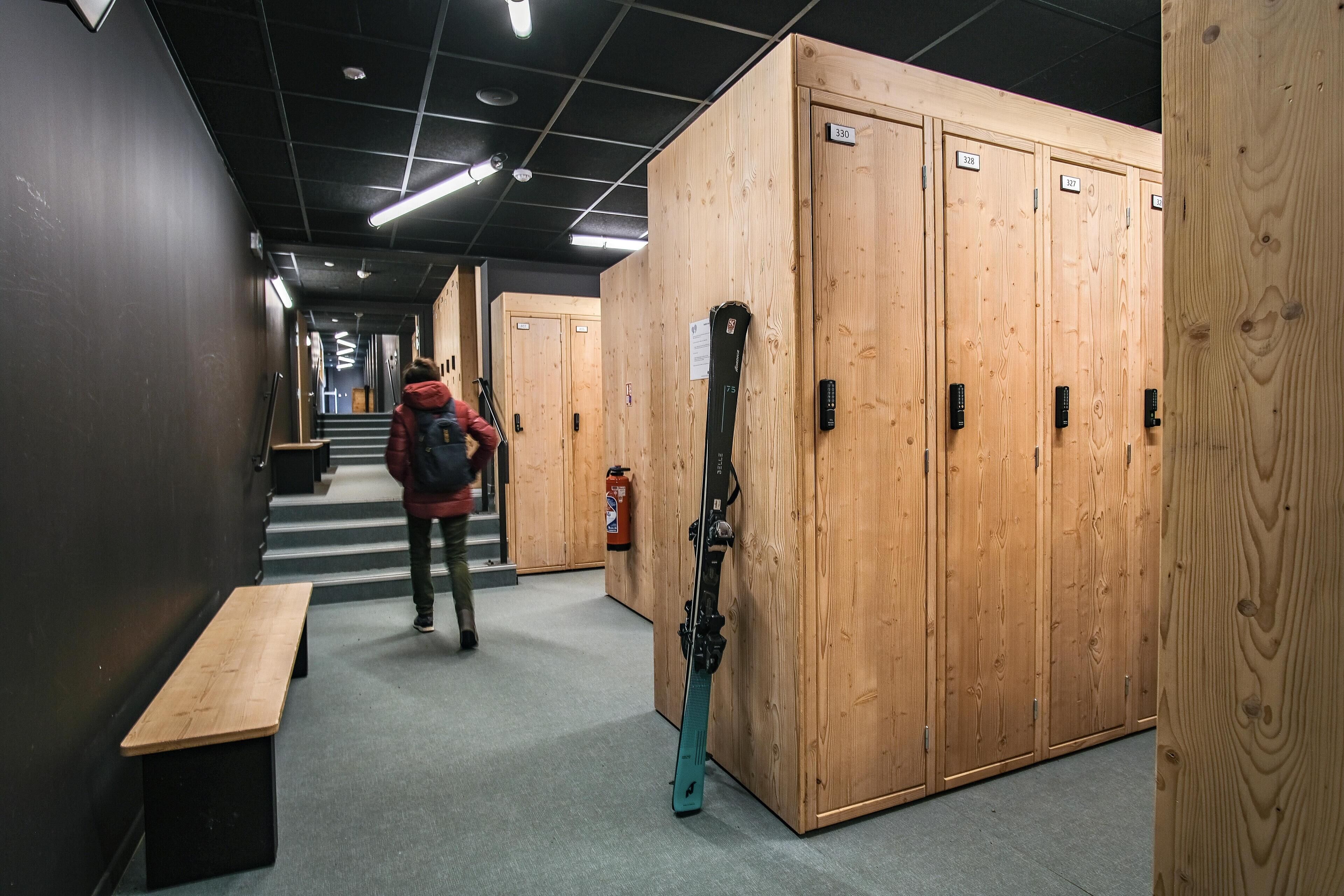A hallway with wooden lockers, a bench, and a ski lift.