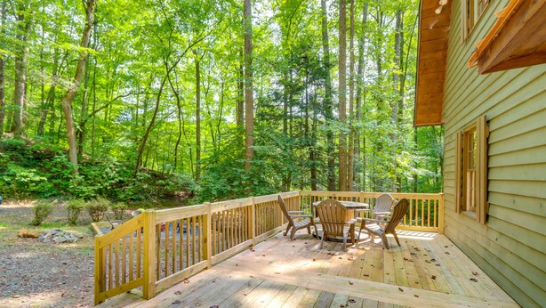 A wooden deck with a table and chairs, surrounded by a forested area. - Wooded Blue Ridge Cabin: 2 Decks, Fire Pit! (Blue Ridge)