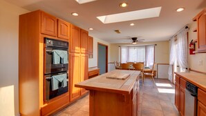 A kitchen with wooden cabinets, a central island, and a dining area with a table and chairs.