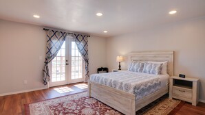 A bedroom with a wooden bed, a nightstand with a lamp, and a clock.