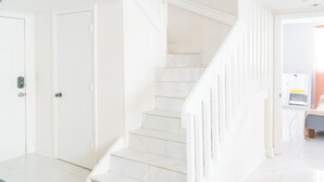Eine Treppe mit weißen Geländern führt zu einem Zimmer mit einem Bett und einem Fenster.