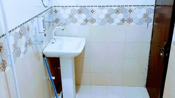 A small bathroom with a white sink, a toilet, and a shower.