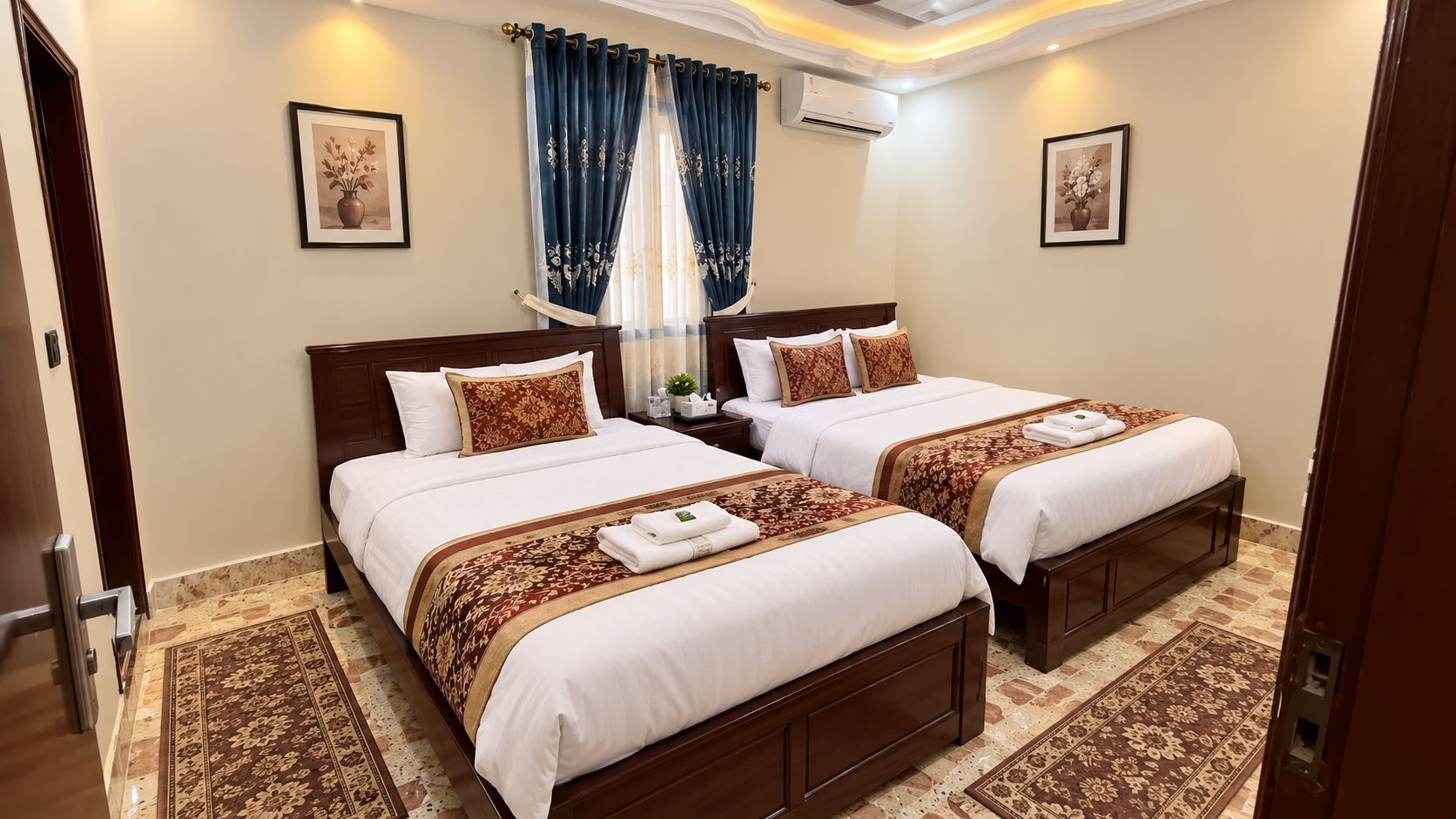 Habitación de hotel con dos camas, un ventanal con cortinas, aire acondicionado de pared y un cuadro enmarcado.