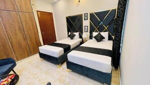 Una habitación de hotel con dos camas, un armario y una silla.