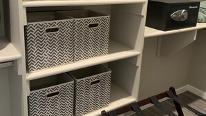 Un depósito con estantes y cajones múltiples, algunos con cajas de almacenamiento decoradas y una caja fuerte negra.
