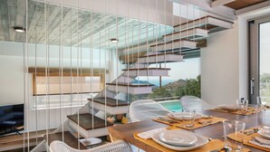 Un intérieur moderne avec un escalier, un coin repas et une vue sur l’extérieur.