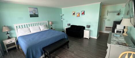 A room with a bed, bedside tables, a bench, a desk, a chair, and a small table.