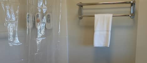 Ein Badezimmer mit Duschvorhang, Toilette, Handtuchhalter und WC-Bürste.