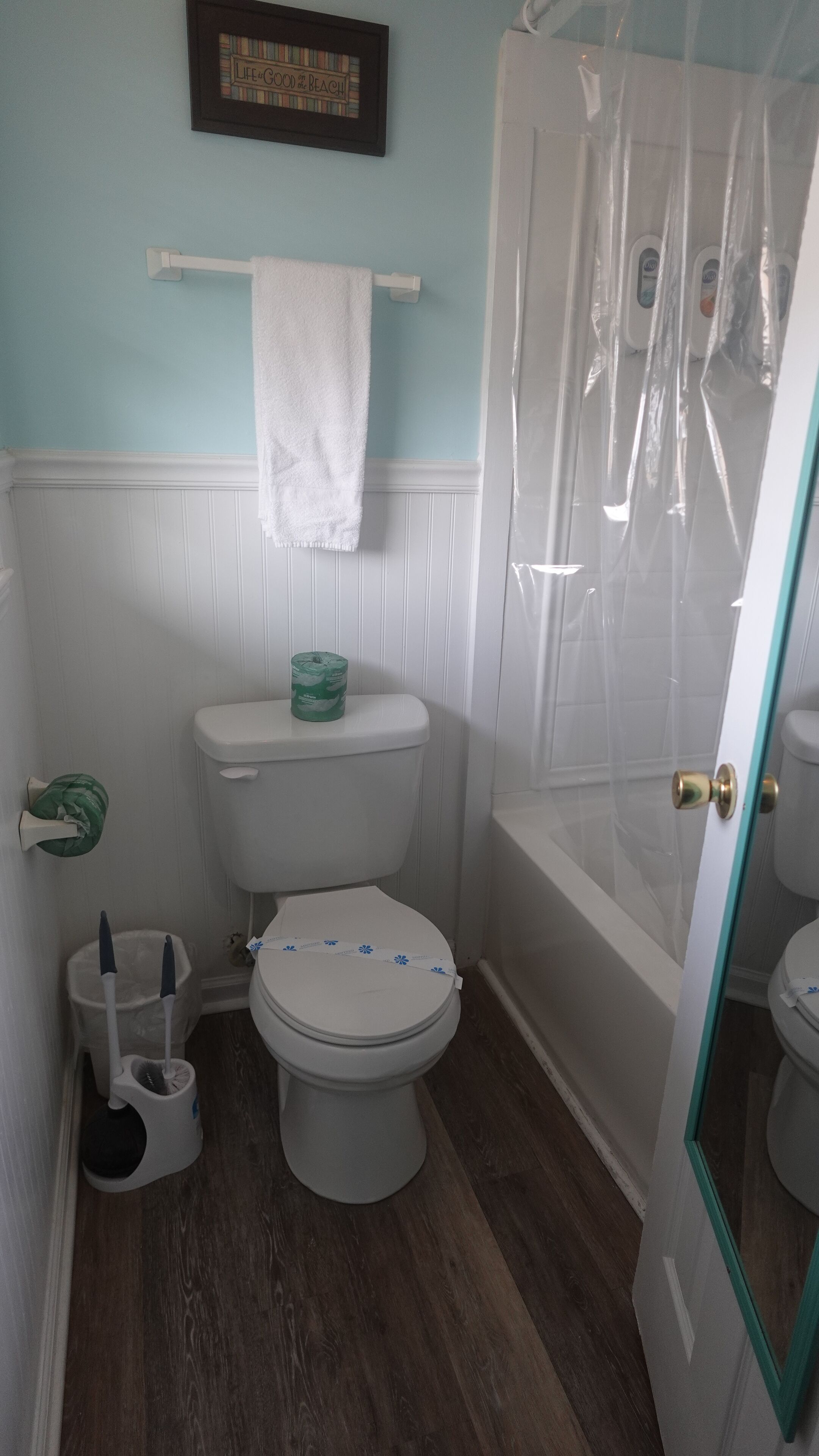 A bathroom with a toilet, a shower curtain, a towel rack, and a toilet paper holder.