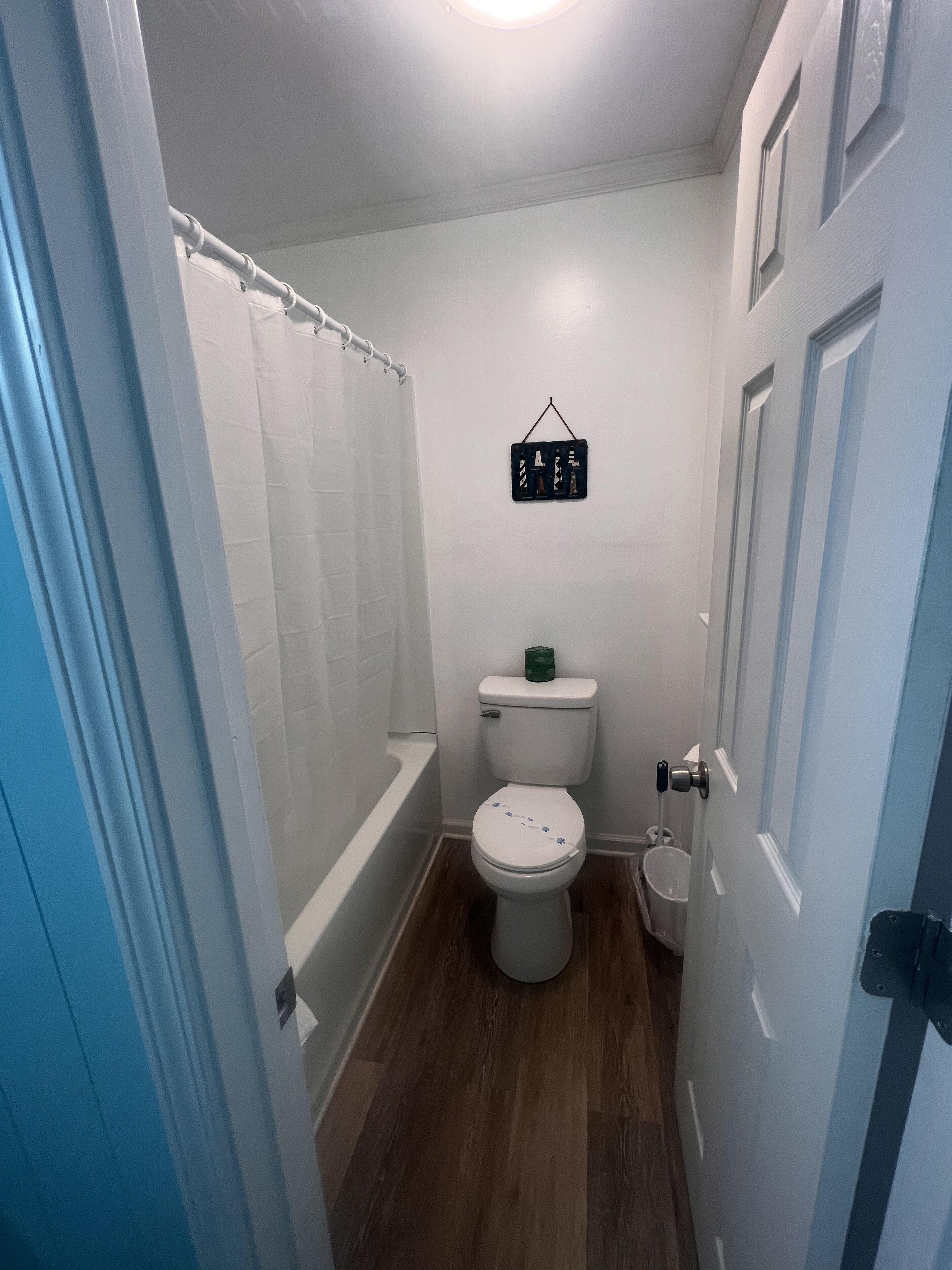 Un baño con inodoro, cortina de ducha, dispensador de papel higiénico colgante y bañera.