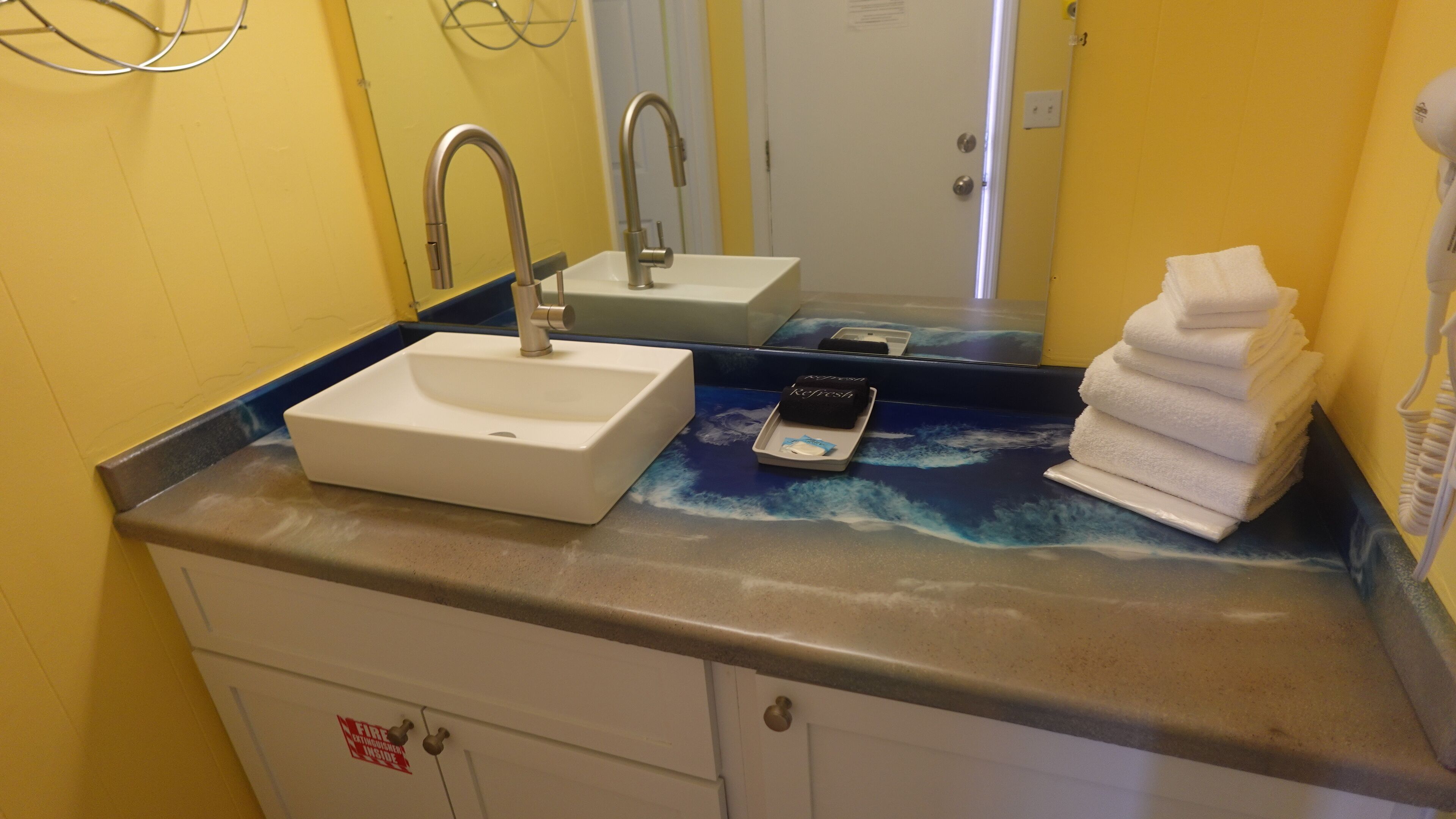A bathroom with a white sink, a mirror, and a towel rack.
