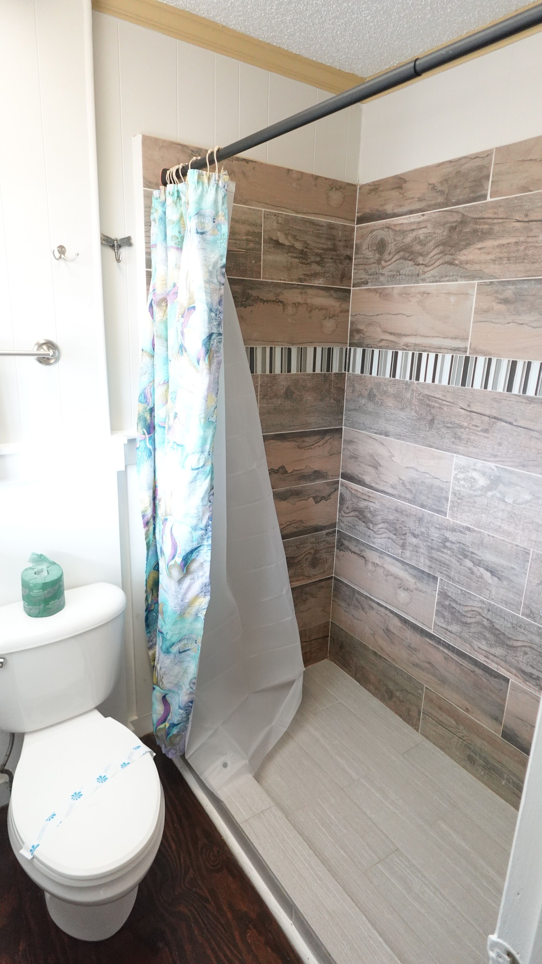 A bathroom with a shower, toilet, and a curtain.