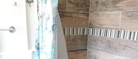 A bathroom with a shower, toilet, and a curtain.