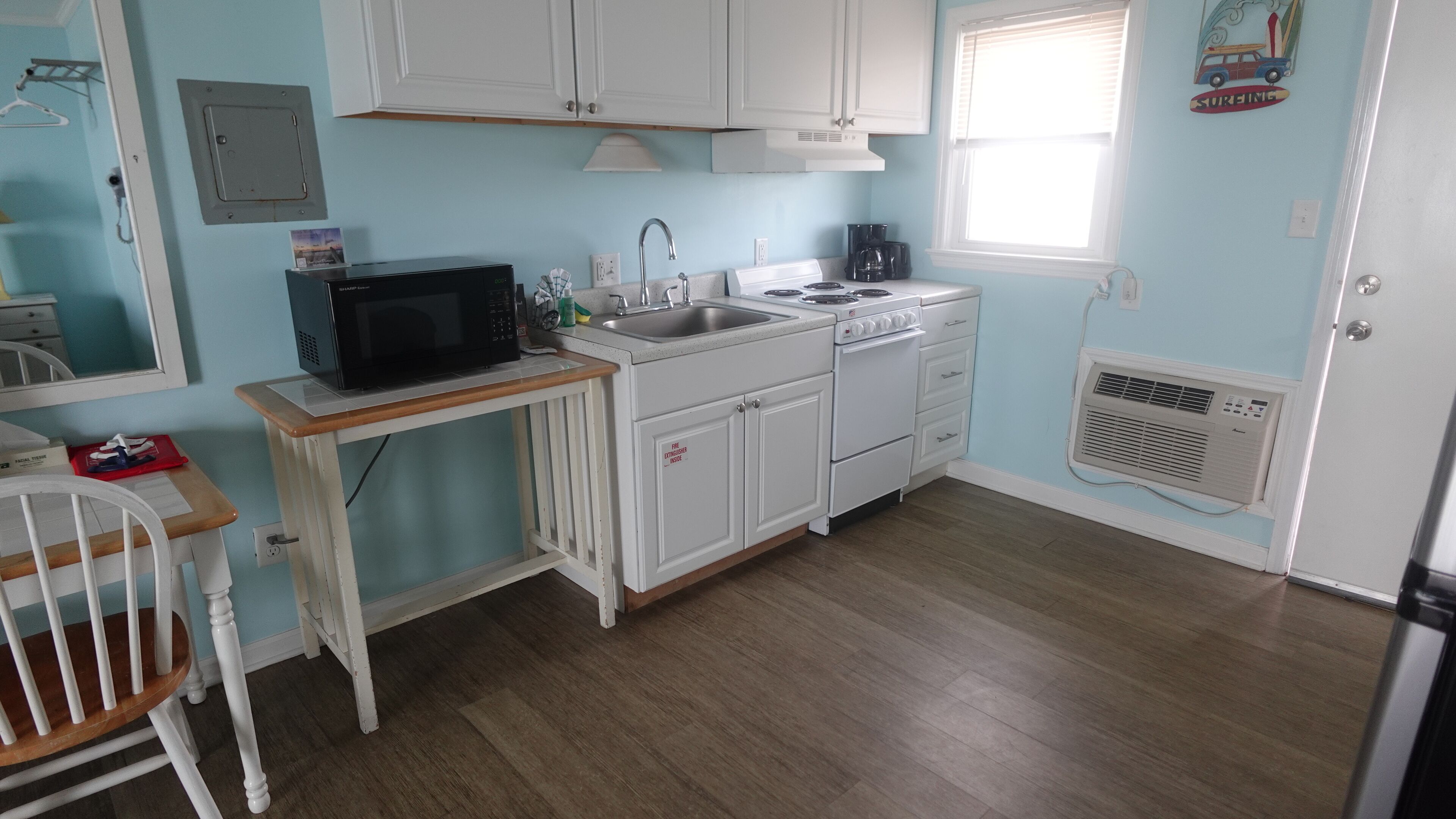 A compact kitchen with white cabinets, a microwave, a sink, and a stove.