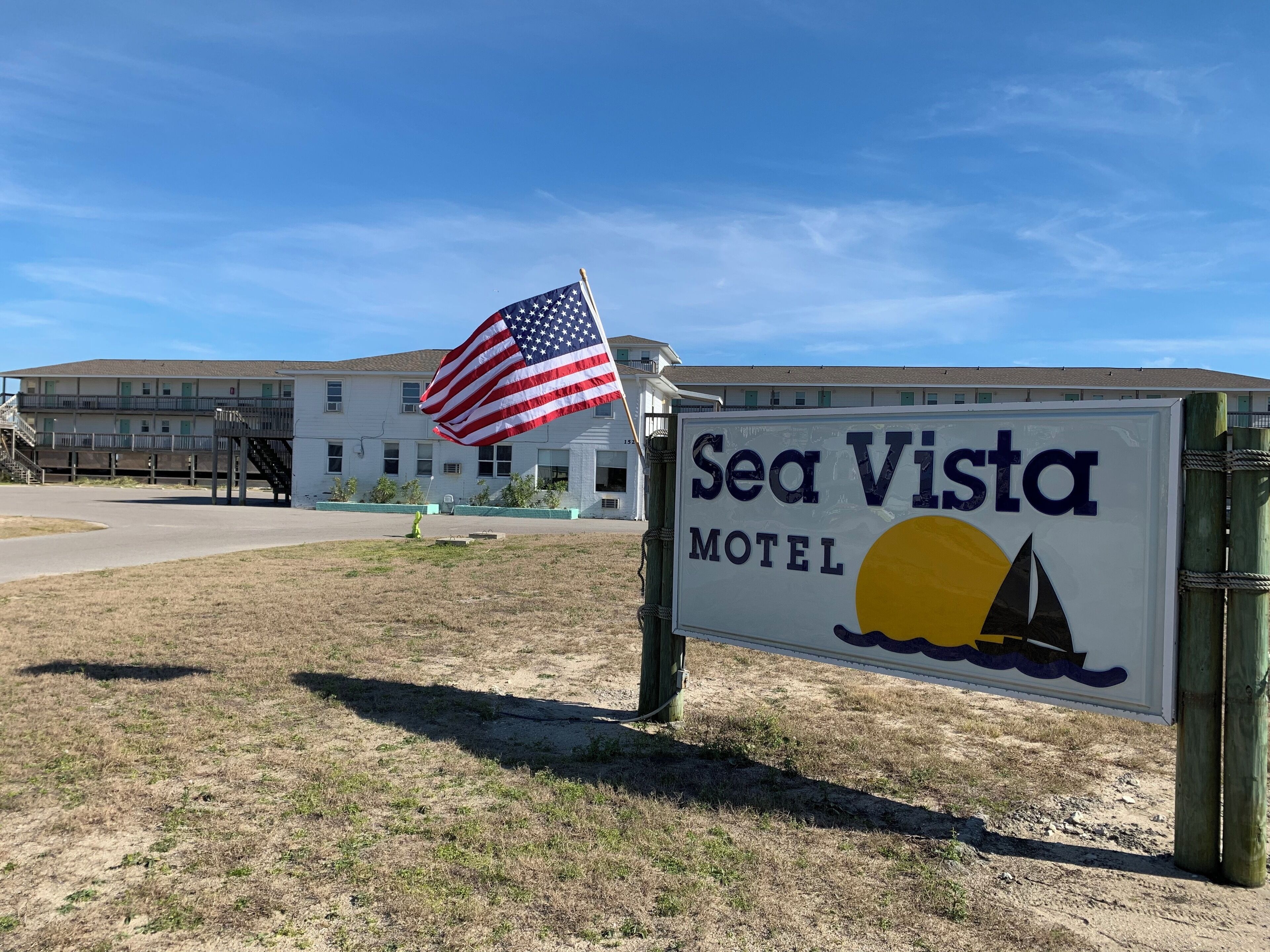 A motel sign with an American flag, a sailboat, and a sun.