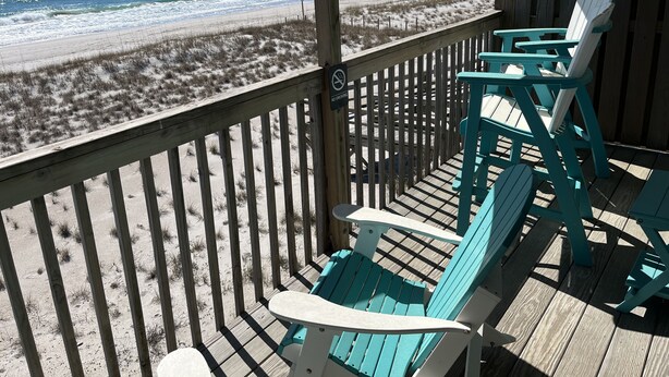 A wooden deck with turquoise chairs overlooking a beach. - Sea Vista Motel (Holly Ridge)