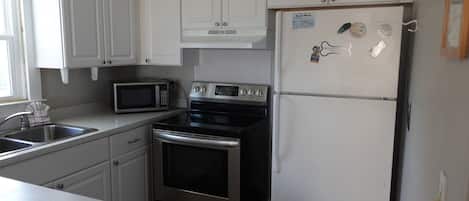 A kitchen with white cabinets, a stainless steel microwave, oven, and refrigerator.