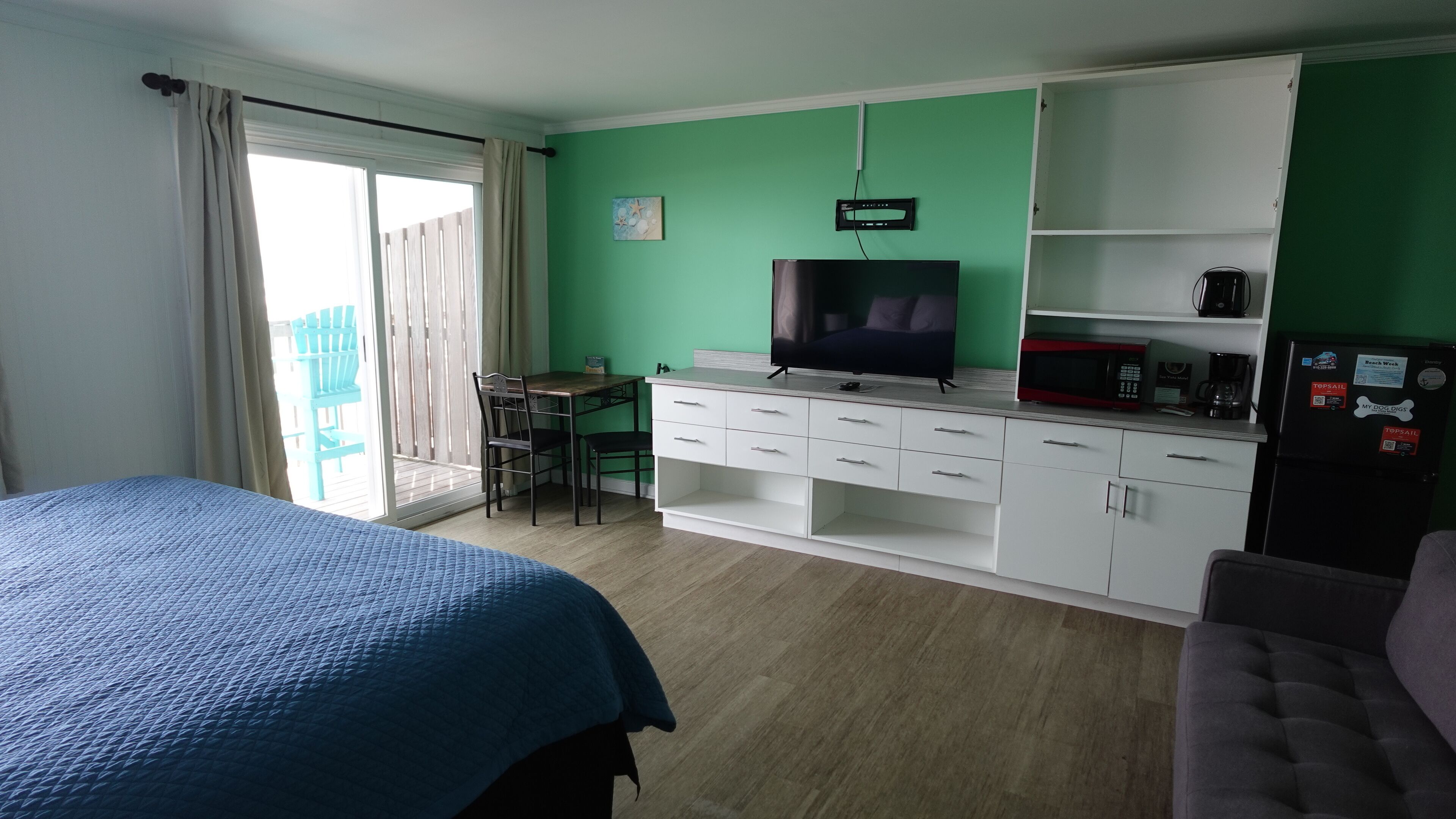 A room with a bed, a desk with a chair, a television, a microwave, and a refrigerator.