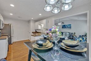 A modern kitchen with white cabinets, a marble countertop, and a dining area with a table set for four.