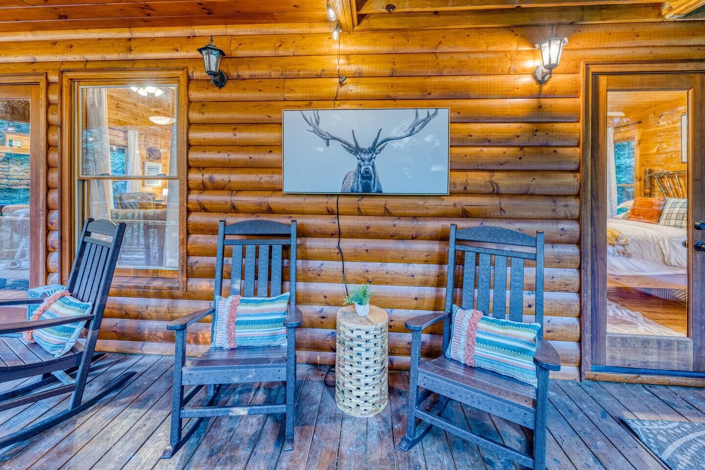 A log cabin interior with two rocking chairs, a framed deer antler artwork, and a small woven basket.