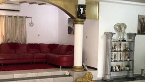 A living room with a red leather sofa, a marble floor, a gold-colored column, and a bookshelf with decorative items.