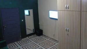 A room with a patterned floor, a door, a mirror, and a wardrobe.