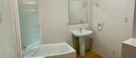A bathroom with a bathtub, sink, toilet, and a glass-enclosed shower area.
