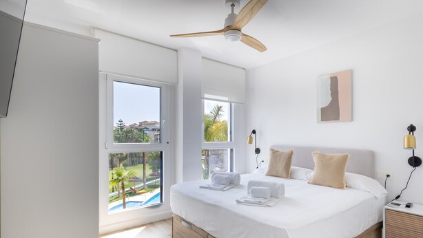 A modern bedroom with a large bed, a ceiling fan, and a view of a swimming pool. - Homity Exclusive Ab-3-c6-2d (Motril)