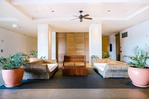 Una habitación de hotel con una cama, un banco de madera y dos plantas en macetas.