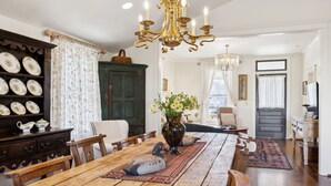 Un comedor con una mesa de madera, sillas, una araña y un florero con flores.
