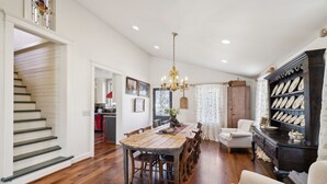 Un salón comedor amplio con una mesa de madera, una araña y una estantería.