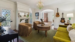 A living room with a fireplace, a round wooden coffee table, a green sofa, and a chandelier. - Historic Leiper's Fork Inn (Williamson County)