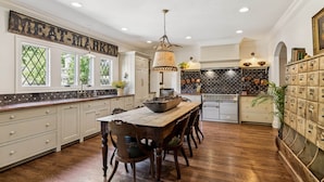 A spacious kitchen with a wooden table and chairs, a hanging light fixture, and a decorative sign on the wall. - Historic Leiper's Fork Inn (Williamson County)