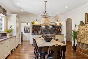 Una cocina amplia con una mesa de comedor de madera, armarios blancos y un candelabro decorativo.