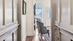 A hallway with a wooden floor, white walls, and a chair in the distance. - Historic Leiper's Fork Inn (Williamson County)